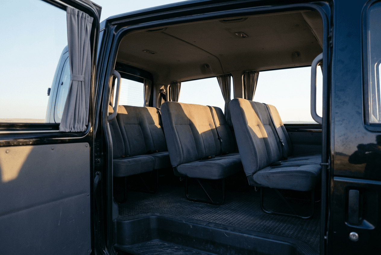Intérieur du minibus 9 places : trois rangées de sièges passagers et allée d’accès latérale, vitres teintées